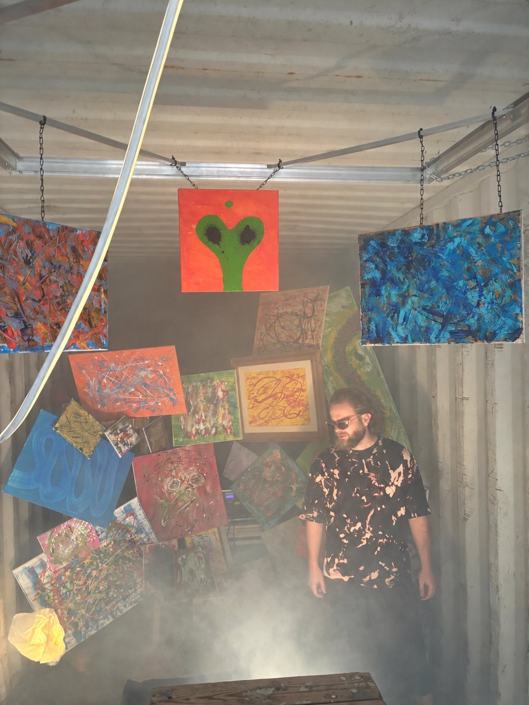 Wessel beside a dense cluster of hanging paintings, the green figure on orange overhead
