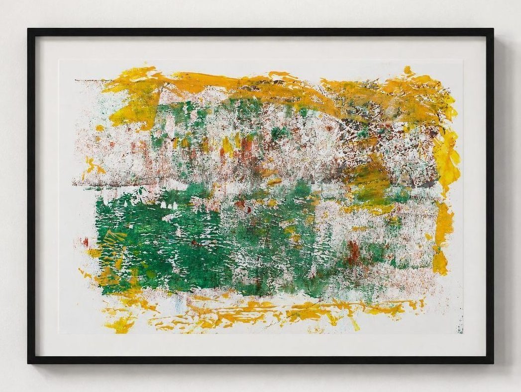 A green and yellow print with orange flecks, in a black frame