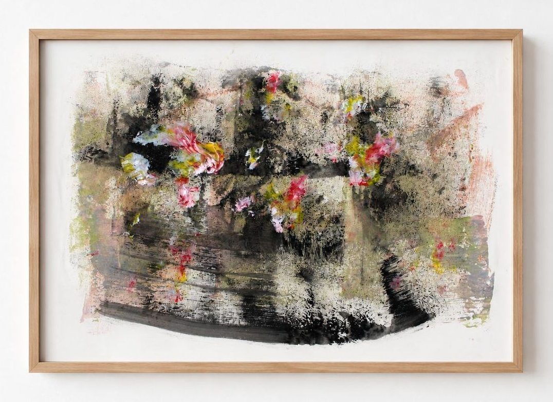 A dark work on paper with pink and yellow blooms, in a pale oak frame